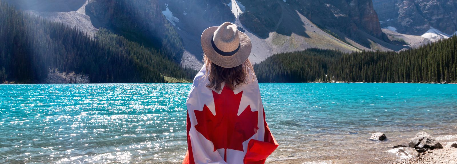female standing in front of ocean holding a Canadian flag